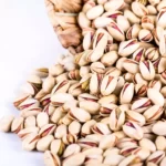 A mass of Akbari pistachios poured from a bowl
