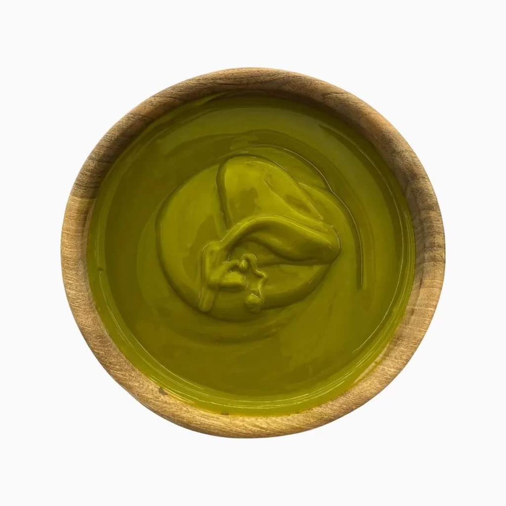 Green pistachio paste in a wooden bowl seen from above.