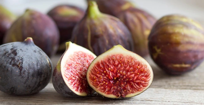 The picture shows a fig fruits with purple skin and red flesh with small white seeds