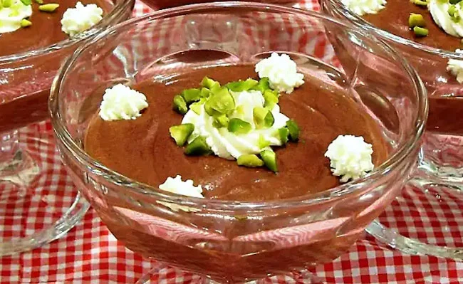 The picture shows a chocolate pistachio mousse in a glass bowl.