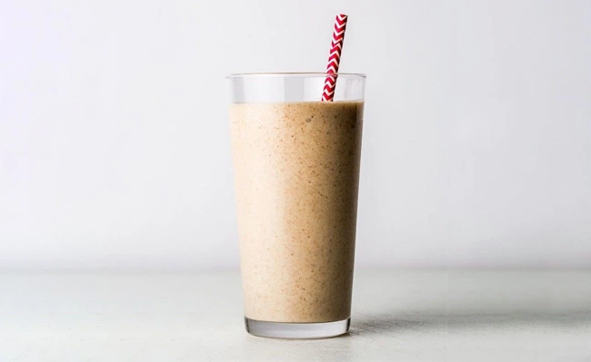 The picture shows a glass of date syrup milkshake