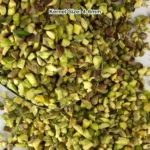 Regular pistachio granules with light green meat and brown skins, from a close view