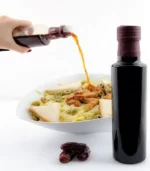 Someone is applying date balsamic vinegar to their salads