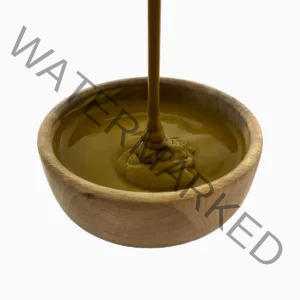 Brown pistachio paste pouring into a wooden bowl