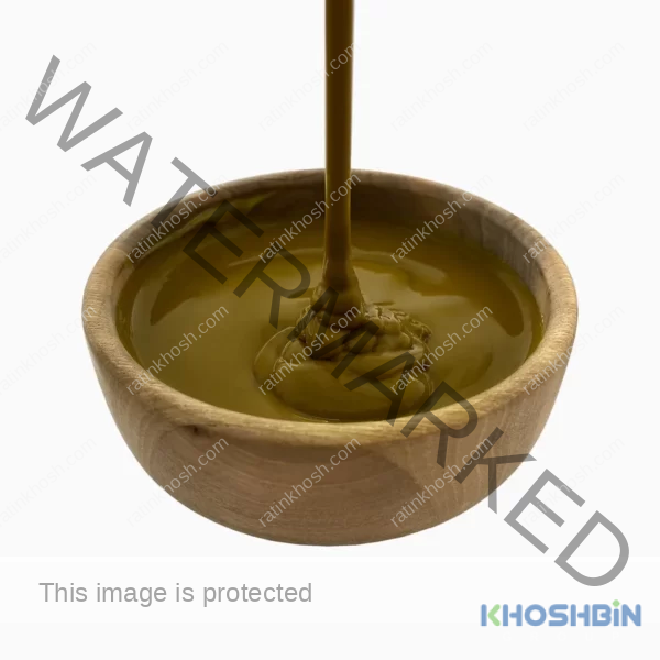 Brown pistachio paste pouring into a wooden bowl