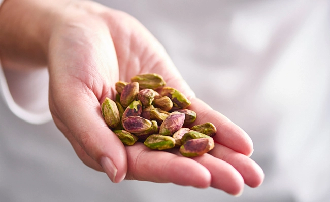 A handful of regular pistachio kernels in a woman's hand